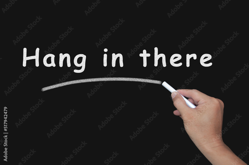 Motivational text written with chalk on blackboard - Hang in there. Motivational concept Motivational text written with chalk on blackboard - Hang in there. Motivational concept