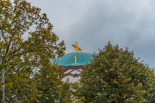 Big golden cross from Saint Sava christian catedral with tree in the foregraound photo