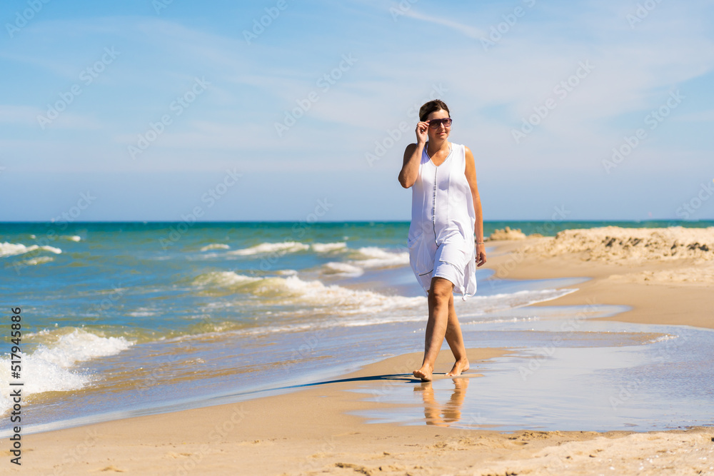 Woman walking on sunny beach
