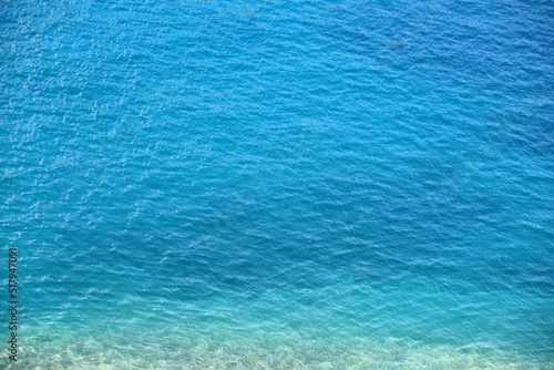 Blue sea water surface with stones on a bottom. Clear turquoise water for background