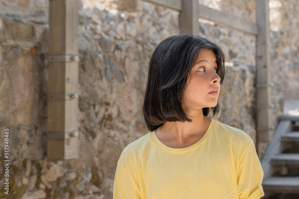 Portrait of a young girl posing against a stone wall. Portrait of a young girl posing against a stone wall.