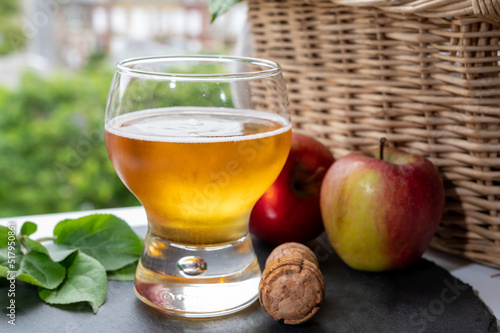 Glass of cold apple cider drink and houses of Etretat village on background, Normandy, France photo