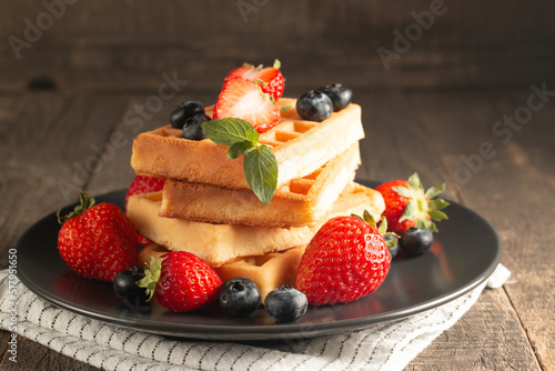 Fresh homemade food of berry Belgian waffles with honey  chocolate  strawberry  blueberry  maple syrup and cream. Healthy dessert breakfast concept with coffee