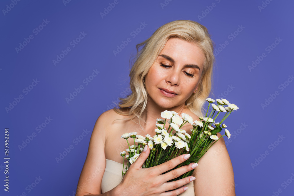 blonde woman with makeup holding white flowers isolated on purple. blonde woman with makeup holding white flowers isolated on purple.
