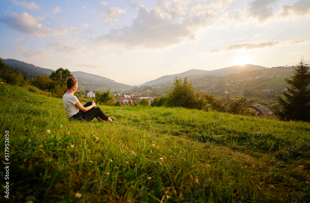 Young woman enjoying the mountains view on the green meadaw.