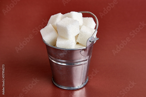 A small bucket with cubes of pressed sugar on a brown background.