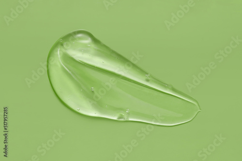 Cosmetic serum gel beauty swatch smear smudge on green color background. Skincare beauty product with bubbles texture.
