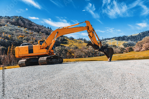 View of a yellow excavator on a rubble mound against a blue sky. Industrial screensaver.