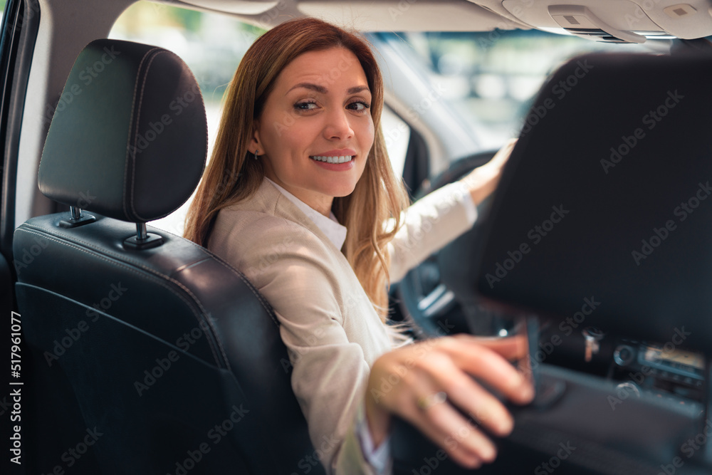 Happy business woman driver sitting in car holding to steering wheel.