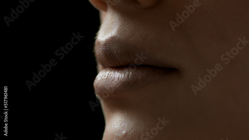 Extreme close-up shot of young African American female model's lips on black background | Lips care concept