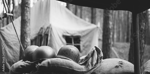 Obraz na płótnie Metal Helmets Of United States Army Infantry Soldier At World War II. Helmets Near Camping Tent In Forest Camp. black and white photography w salonie