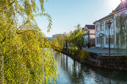 The townscape of Kurashiki Bikan Historical Quarter in sunny day. It is a historic area with old architectures, shops, restaurants and galleries situated along a canal. photo