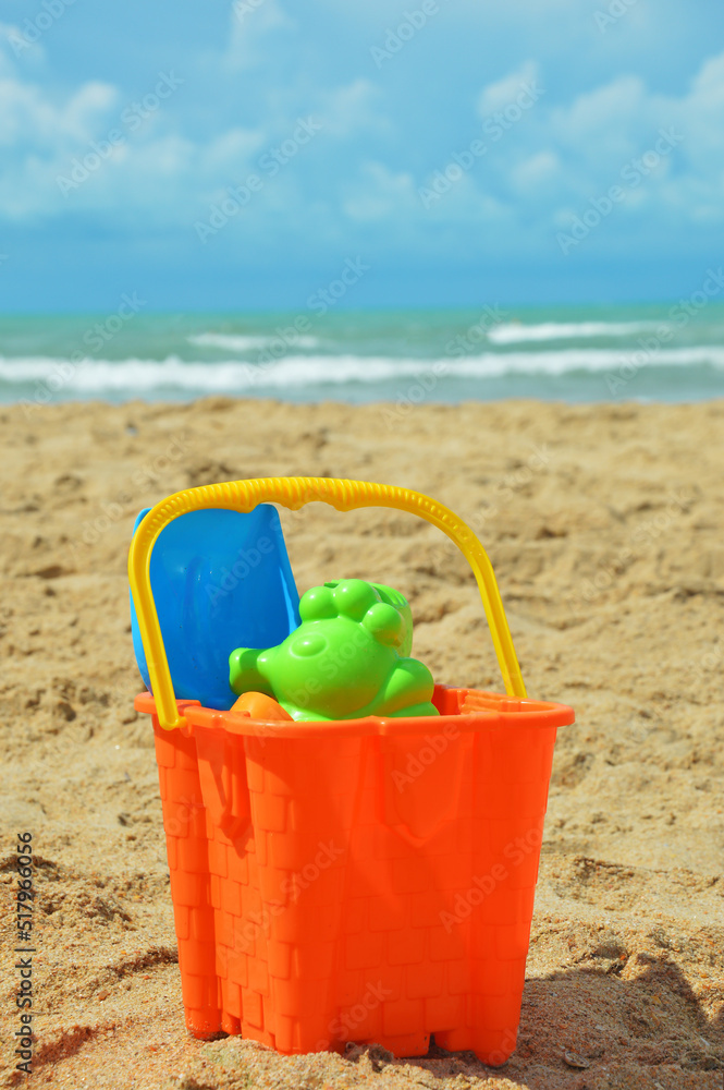 children's toys for sand. against the background of the sea. summer vacation, sun, sand, water. an orange bucket and molds for modeling. children's toys for sand. against the background of the sea. summer vacation, sun, sand, water. an orange bucket and molds for modeling.