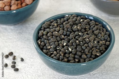 Dry Black lentil (urad sabut) seeds pile in a bowl. photo