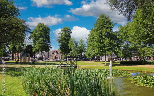 Beautiful idyllic green dutch town park, pond, wood bridge, blue summer sky fluffy clouds - Nuenen, Netherlands photo