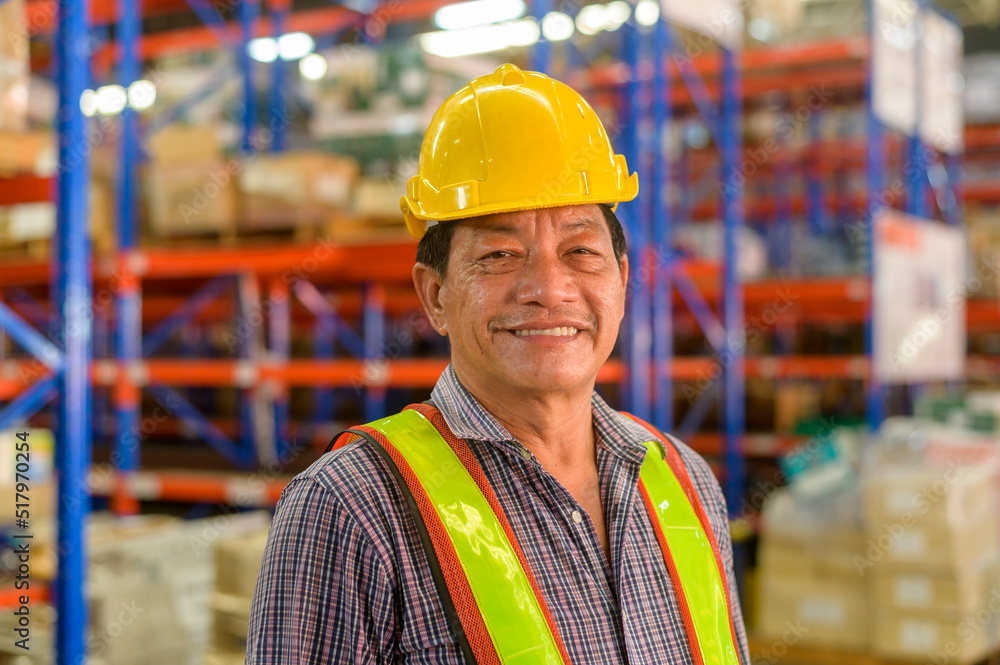 Portrait of senior asian male worker wearing helmet in modern warehouse storage of retail shop Portrait of senior asian male worker wearing helmet in modern warehouse storage of retail shop