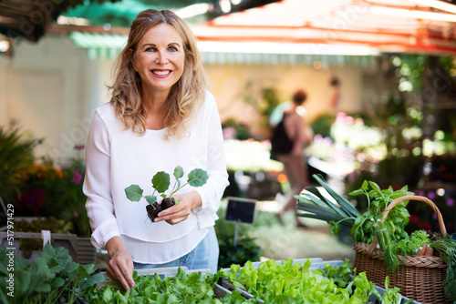Frau auf dem Markt mit kleinen Salatpflänzchen, Freud Gemüse selbst anzubauen photo