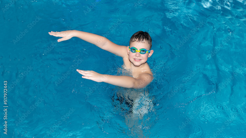 A smiling boy is bathing in the water. Sports and recreation. Healthy lifestyle. Swimming