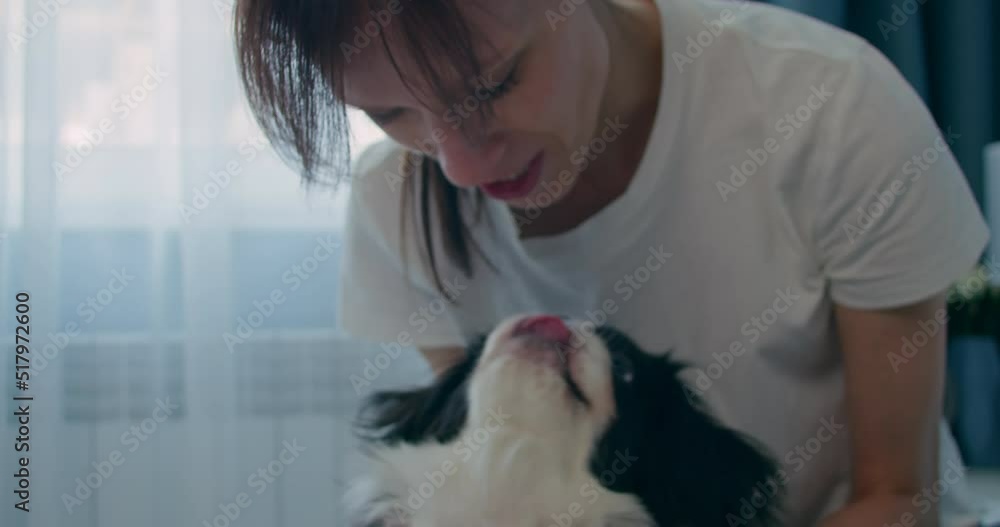 Cheerful woman kiss her cute puppy while relaxing at home. Pets love Cheerful woman kiss her cute puppy while relaxing at home. Pets love