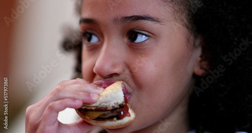 Little girl eating burger. Child taking a bite of hamburger