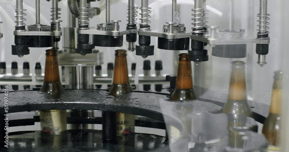 Capping process of full beer bottles. Machine for capping bottles. Factory, brewery concept. Beer bottles on automated machine during capping process. Video of beer bottles moving on a conveyor belt. Capping process of full beer bottles. Machine for capping bottles. Factory, brewery concept. Beer bottles on automated machine during capping process. Video of beer bottles moving on a conveyor belt.