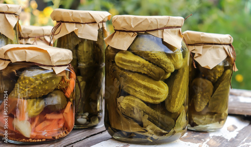 pickled cucumbers in glass jars close-up on a wooden table against the background of a stone wall selective focus