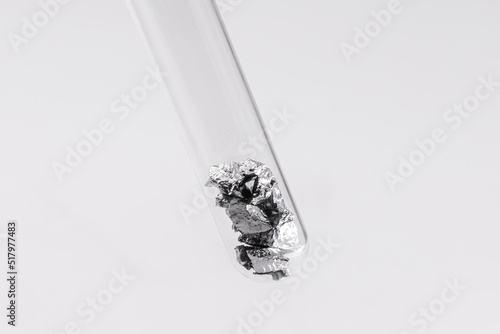 Chromium fragments inside test tube, industrial use ore, metallic chemical element, isolated on white background photo