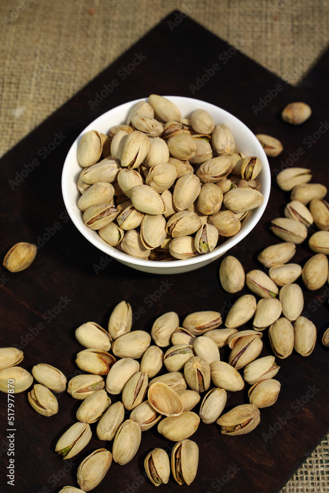 Useful roasted pistachios in a ceramic bowl on a dark wooden background. Useful roasted pistachios in a ceramic bowl on a dark wooden background.