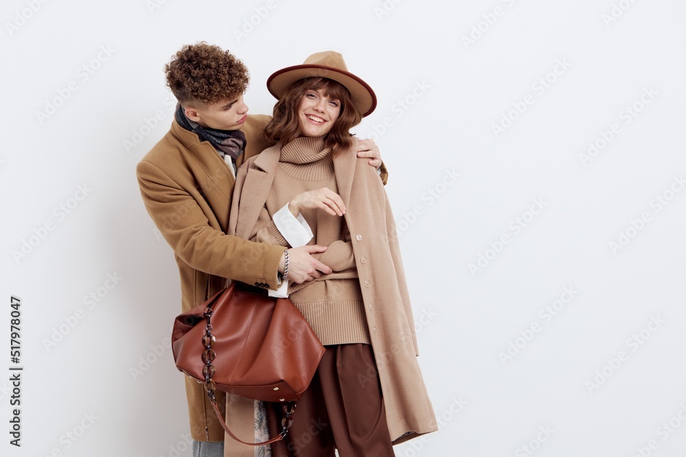a beautiful, loving couple of a man and a woman stand on a white background in stylish autumn clothes, gently embracing and the woman happily looks at the camera, and the man at her a beautiful, loving couple of a man and a woman stand on a white background in stylish autumn clothes, gently embracing and the woman happily looks at the camera, and the man at her