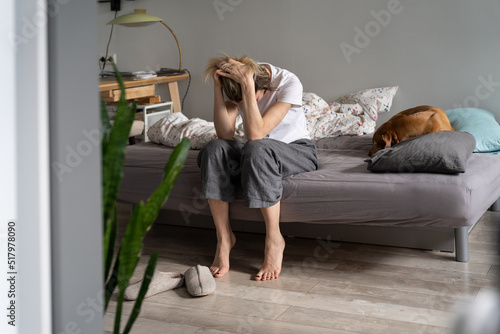 Canvastavla Unhappy woman sitting on sofa holding head in hands suffering from hangover headache in morning, female having personal problems