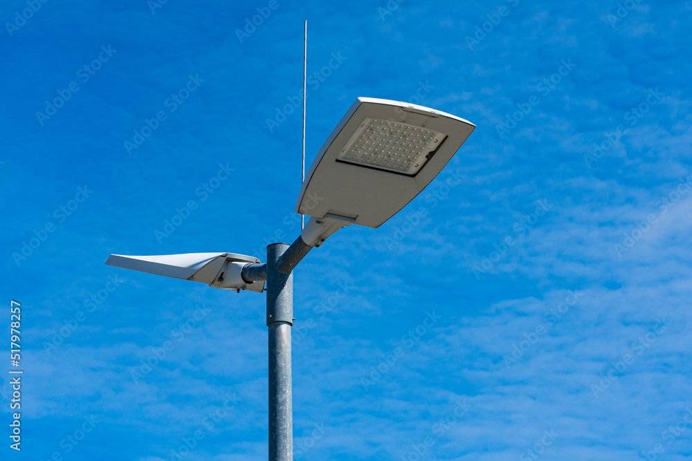 Street lighting lamps on a metal pole. Against a blue sky with light clouds. Street lighting lamps on a metal pole. Against a blue sky with light clouds.
