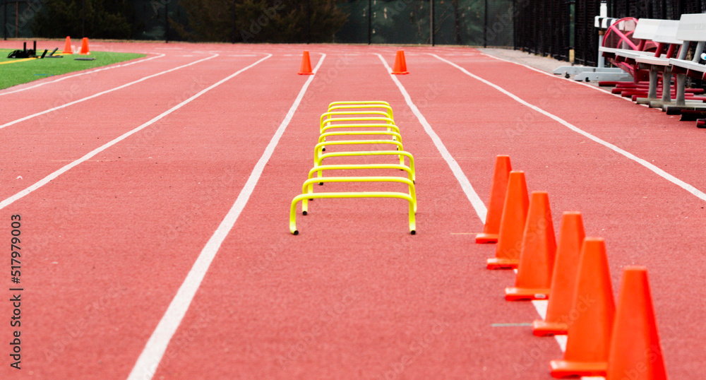 Orange cones and yellow mini hurdles set up on the track for runners to run over
