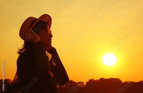 Silhouette of a woman in hat looking up at the sunrise sky
