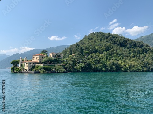 Landscape of Como Lake shore and Villa del Balbianello mansion house surrounded by trees. Emerald blue water. Tremezzo, Como Lake, Lombardy, Italy