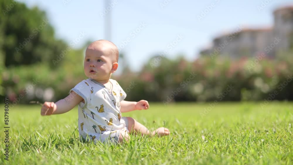 Cute baby boy sitting on the green grass and crawling summer day Cute baby boy sitting on the green grass and crawling summer day