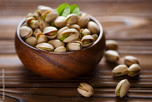 Delicious pistachios in wooden bowl on wooden background