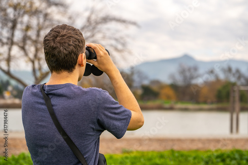 A man looking through binoculars at mountains. Travel concept. 