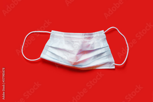 Danger of viral infection. Disposable medical mask. Protection against respiratory infection. Isolate on a red background