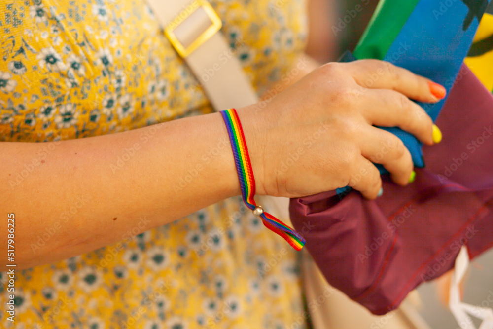 Rainbow bracelet as a symbol of pride month on female hand. people at pride parade