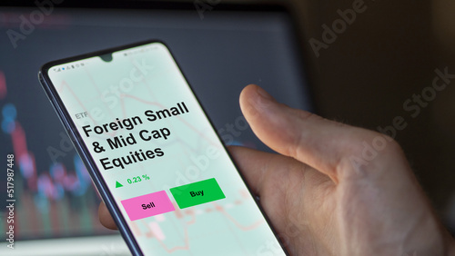 Fonds ETF d'actions étrangères à petite et moyenne capitalisation sur un écran. Un téléphone affiche les prix des actions étrangères à petite et moyenne capitalisation, texte en anglais.
