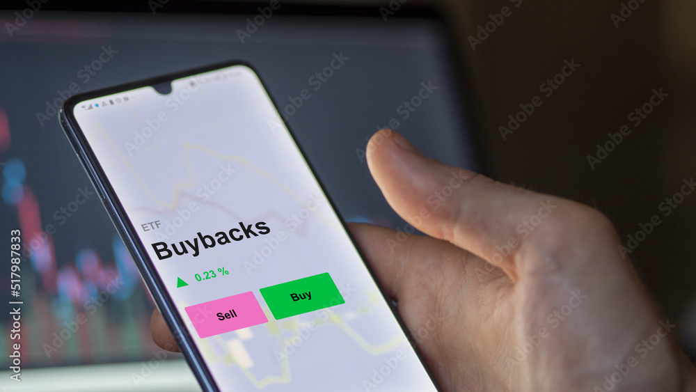 An investor's analizing the buybacks etf fund on a screen. A phone shows the prices of Buybacks An investor's analizing the buybacks etf fund on a screen. A phone shows the prices of Buybacks