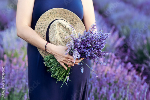 Fototapeta Naklejka Na Ścianę i Meble -  woman with straw hat and lavender bouquet in her hands in lavender field in summer. Travel, herbs, flowers concept
