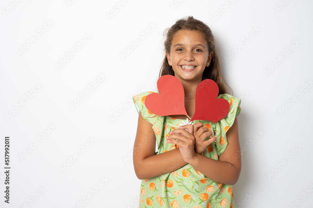 Happy girl with two carton paper small little heart figures standing isolated over white background. Love concept. Happy girl with two carton paper small little heart figures standing isolated over white background. Love concept.