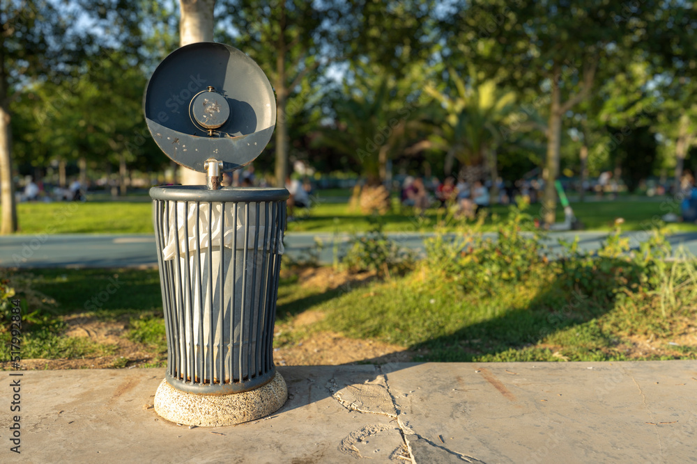 metal trash can in park, selected focus, black color with lid metal trash can in park, selected focus, black color with lid