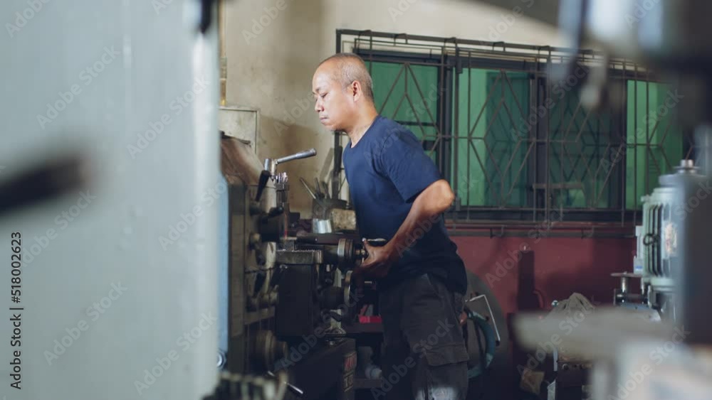 Technician asia worker using turning lathe machine for metalworking in workshop factory Technician asia worker using turning lathe machine for metalworking in workshop factory
