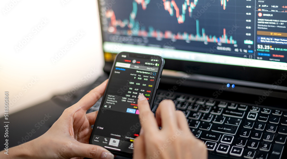Female trader investor broker analyst holding a smartphone in hand analyzing stock market trading charts indexes data checking price using mobile Female trader investor broker analyst holding a smartphone in hand analyzing stock market trading charts indexes data checking price using mobile