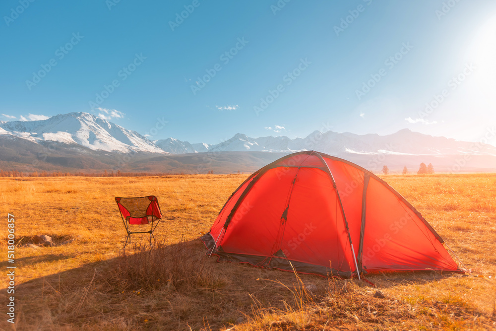 Bright red tourist tent in Altai mountains sunset, beautiful view nature. Concept travel hiking autumn