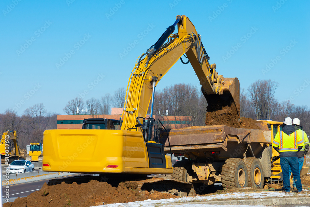Loader excavator loads the ground in the truck at the road construction Loader excavator loads the ground in the truck at the road construction