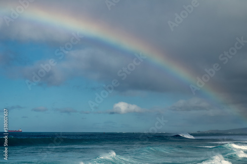 rainbow over the sea with passing rain showers. © ttrimmer