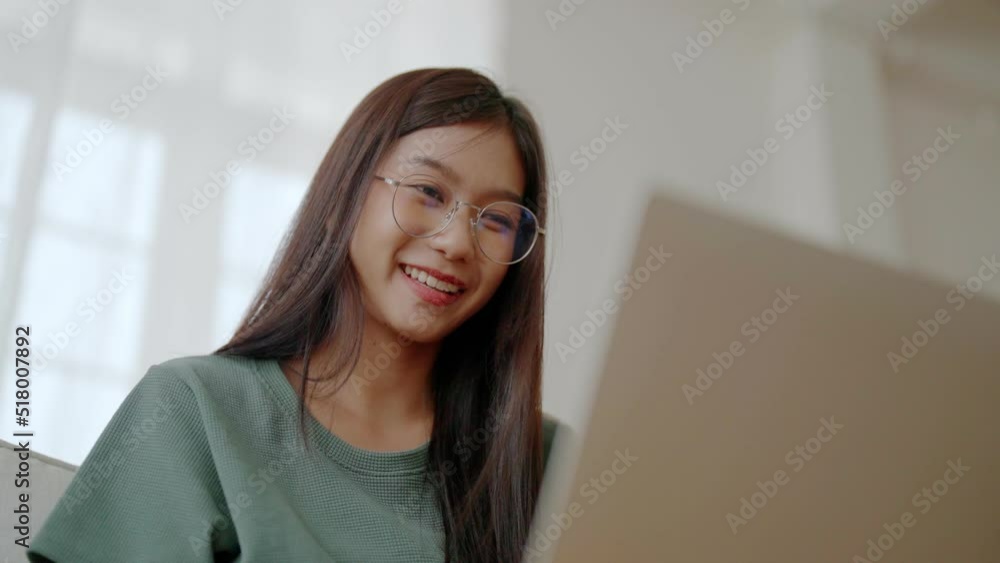 Smiling young asian woman working on laptop at home. Attractive asia female using computer remote studying, watching online education and video calling Smiling young asian woman working on laptop at home. Attractive asia female using computer remote studying, watching online education and video calling